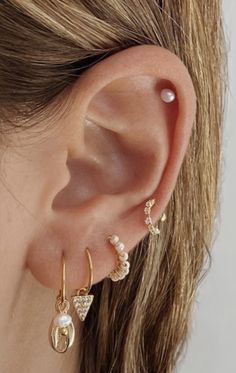 a close up of a person's ear with two different types of earrings on it