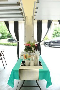 a table with bottles and glasses on it in front of a car parked outside the building