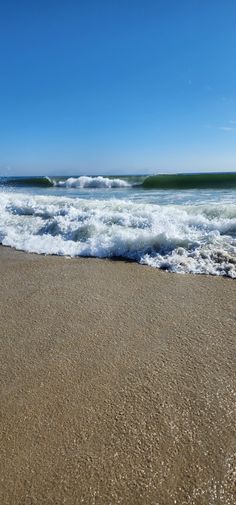 the ocean waves are rolling in and out of the water on a sunny day at the beach