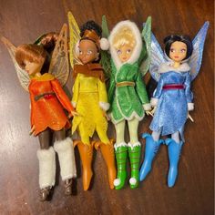 five toy tinkerbells lined up on a table