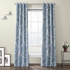 the curtains in this room are blue with white flowers on them, and one window is closed