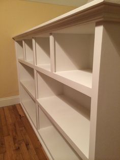 an empty white bookcase in the corner of a room