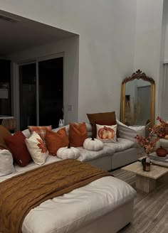 a living room filled with lots of white furniture and orange pillows on top of it