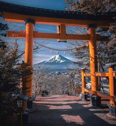 an orange gate leading to a mountain with snow on the top and trees in the foreground