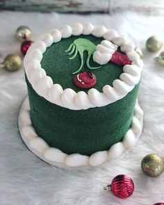 a green and white christmas cake with decorations around it