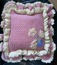 a crocheted pillow with flowers on it sitting on top of a black chair