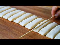 a person is cutting up some food on a wooden board with a toothpick