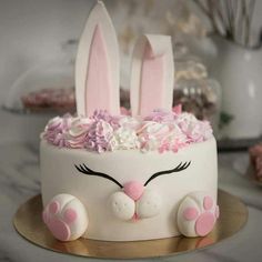 a white cake decorated with pink flowers and bunny ears