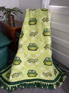 a green and white frog blanket on the floor