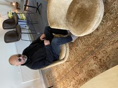 a man sitting on a chair in a living room next to a table and chairs