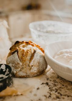 a loaf of bread sitting on top of a counter next to a bowl of cream cheese