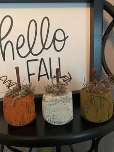 three small pumpkins sitting on top of a black table next to a sign that says hello fall