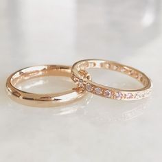 two gold wedding rings sitting on top of a white countertop next to each other