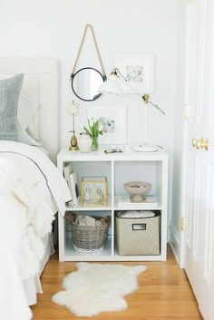 a bedroom with white walls and wooden flooring, a small shelf filled with items