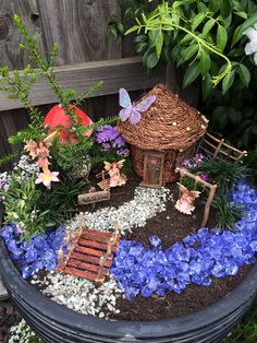 a potted planter filled with lots of flowers and miniature fairy houses on top of it