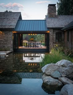 an outdoor dining area next to a pond with lights on the patio and tables in the water