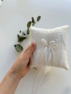 a hand holding a white pillow on top of a table