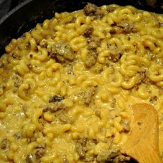 macaroni and cheese is being cooked in a skillet with a wooden spoon