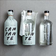 three empty bottles sitting next to each other on top of a gray surface with white paper