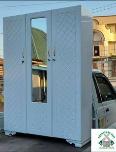 a white car parked in front of a tall cabinet with mirrors on it's doors