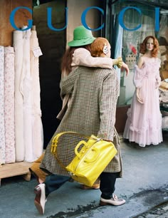 a woman walking down the street carrying a yellow handbag in front of mannequins