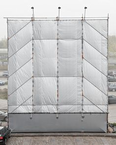 a white tarp covering a parking lot next to a black car