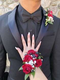 a man in a tuxedo with red roses and white flowers on his wrist