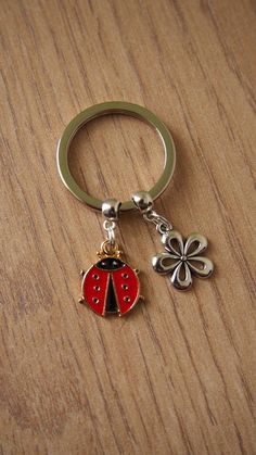 a ladybug keychain with a clover charm on it sitting on a wooden surface