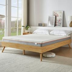 a bed with a wooden frame and mattress on top of it in a room next to a window