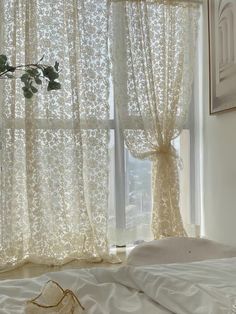 a white bed sitting next to a window covered in curtains