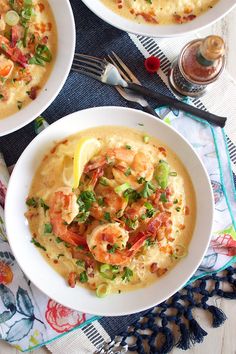 two white bowls filled with shrimp and grits on top of a blue table cloth