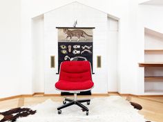 a red chair sitting on top of a white rug in front of a black and white wall