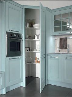 a kitchen with blue cabinets and an oven in the corner, is shown from the doorway