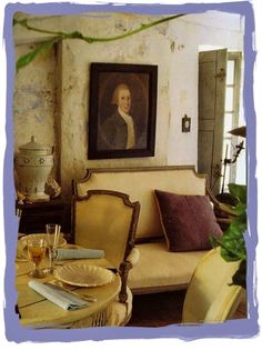 a painting hangs on the wall next to a table and chairs in a living room