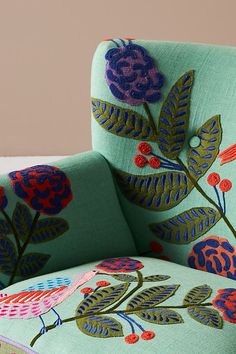 an upholstered green chair with colorful flowers and leaves on the armrests