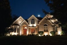 a house lit up at night with lights on the front and side of the house