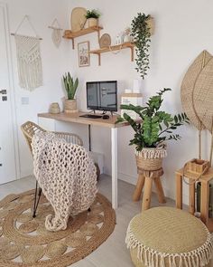 a home office with wicker furniture and plants on the desk, in front of a white wall