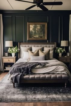 a bedroom with dark green walls and white bedding, an upholstered headboard,