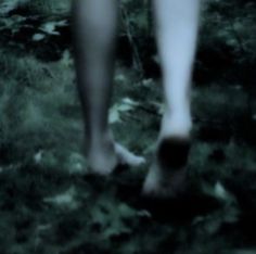 a blurry photo of a person's legs and feet walking in the grass