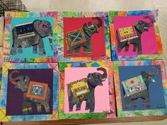 four elephant paintings are displayed on a colorful table cloth covered with paper and colored squares