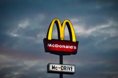 a mcdonald's restaurant sign with a cloudy sky in the background