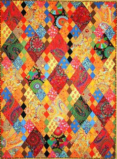 an orange and red quilt with many different designs on it's sides, including the center