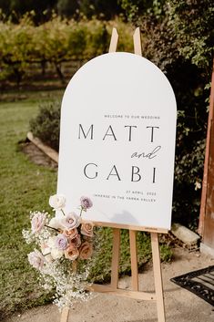 a sign that says mat and gabi on it with flowers in the foreground