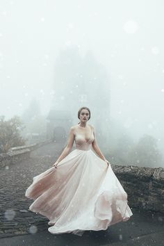 a woman in a pink dress is walking through the foggy ground with her hands on her hips