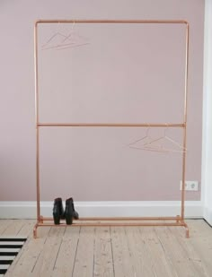 a pair of black shoes sitting on top of a wooden floor next to a pink wall