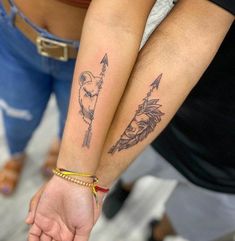 two people holding hands with tattoos on their arms and one has an arrow in the middle