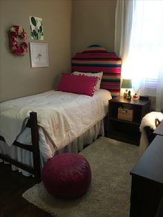 a bed room with a neatly made bed next to a window and a rug on the floor