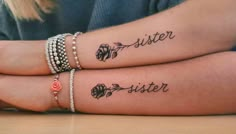 two people with matching tattoos on their arms sitting next to each other and holding hands