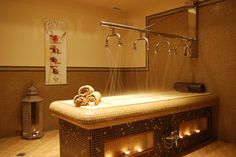 a large bath tub with candles and towels on it in a tiled room next to a towel rack