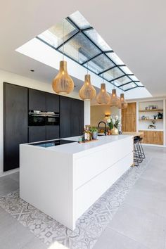 a kitchen with an island and skylight in the ceiling, along with modern lighting fixtures